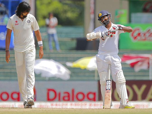 Sharma, left, walks back toward his run-up after bowling to Thirimanne. (AP Photo)