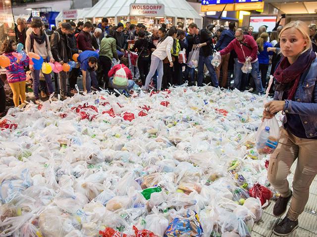 People surround hundreds of bags containing food as they wait for the arrival of a special train from Austria transporting hundreds of migrants at the main train station in Frankfurt am Main, western Germany. Germany expected up to 7,000 migrants who have been stuck in Hungary to cross into the country via Austria on Saturday. (AFP Photo)