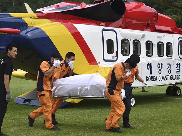 A victim's body who was on board a capsized fishing boat in the water off the resort island of Jeju, is carried by rescue workers upon its arrival in Haenam, South Korea. (Newsis via AP Photo) A victim's body who was on board a capsized fishing boat in the water off the resort island of Jeju, is carried by rescue workers upon its arrival in Haenam, South Korea. (Newsis via AP Photo)