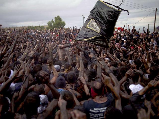 People covered in black grease congregate around a black banner during the traditional festivities of the Cascamorras. (AFP Photo)