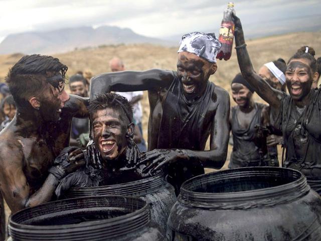 People covered in black grease push a man into a drum during the traditional festivities of Cascamorras. (AFP Photo)