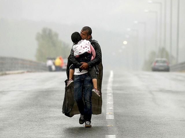 A Syrian refugee kisses his daughter as he walks through a rainstorm towards Greece's border with Macedonia, near the Greek village of Idomeni. (Reuters Photo)