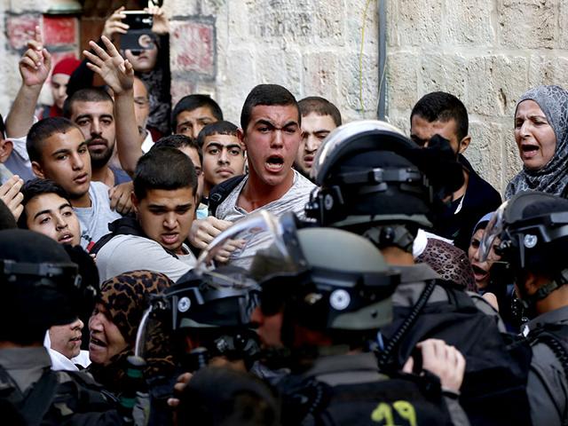 Palestinians shout in front of Israeli security forces who block a road leading to the Al-Aqsa mosque compound in Jerusalem's Old City. Palestinians clashed with Israeli police. (AFP Photo)