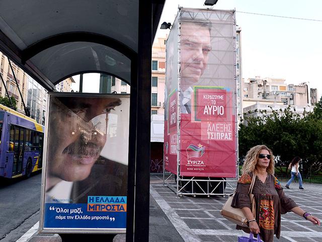 A woman walks past pre-election posters featuring conservative New Democaracy leader Vangelis Meimarakis (L) and leftist Syriza leader Alexis Tsipras in central Athens. (AFP Photo)