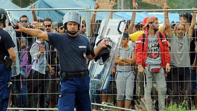 Police officers guard a local refugee camp in Roszke, Hungary, on September 4, 2015. Hungarian police had temporarily shut the Roszke border crossing with Serbia after 300 migrants escaped from the camp. (AFP) Police officers guard a local refugee camp in Roszke, Hungary, on September 4, 2015. Hungarian police had temporarily shut the Roszke border crossing with Serbia after 300 migrants escaped from the camp. (AFP)