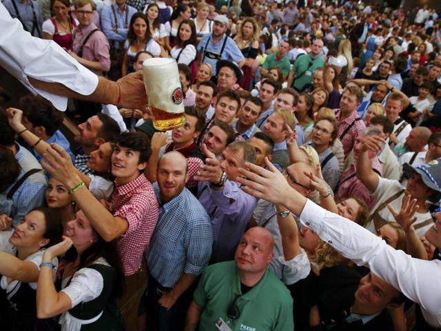 Visitors reach for a mug of beer from the first barrel during the opening ceremony for the 182nd Oktoberfest in Munich , Germany on Saturday. Millions of beer drinkers from around the world will come to the Bavarian capital over the next two weeks for Oktoberfest, which runs until October 4. (REUTERS)