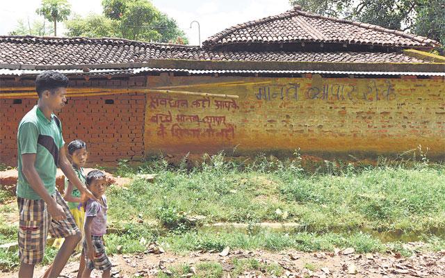 A man and two children walk past a wall bearing a warning message on human trafficking in a village in Khunti district. Such warnings are a common sight in these areas. ((Vipin Kumar/HT Photo)) A man and two children walk past a wall bearing a warning message on human trafficking in a village in Khunti district. Such warnings are a common sight in these areas. ((Vipin Kumar/HT Photo))