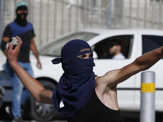 A masked Palestinian youth throws stones towards Israeli security forces during clashes in the Palestinian refugee camp of Shuafat in east Jerusalem. (AFP Photo) A masked Palestinian youth throws stones towards Israeli security forces during clashes in the Palestinian refugee camp of Shuafat in east Jerusalem. (AFP Photo)
