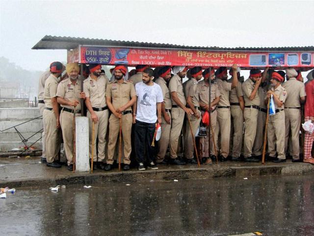 Policemen stand under a shelter during rainfall in Bathinda on Sunday. (PTI)