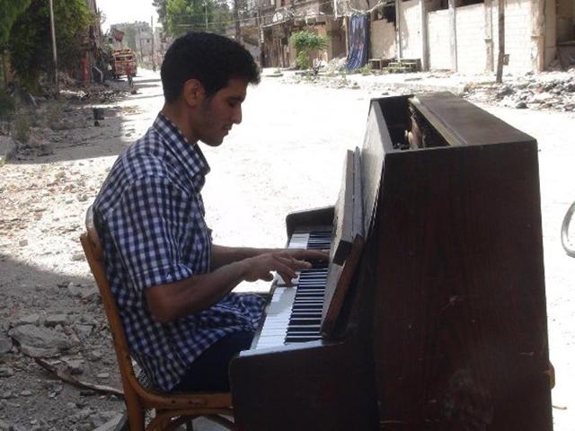 A file picture shows Aeham al-Ahmad, a former resident of Damascus' Yarmuk Palestinian refugee camp, being helped by a friend to push his piano along a the street in the southern Damascus suburb. (AFP) A file picture shows Aeham al-Ahmad, a former resident of Damascus' Yarmuk Palestinian refugee camp, being helped by a friend to push his piano along a the street in the southern Damascus suburb. (AFP)