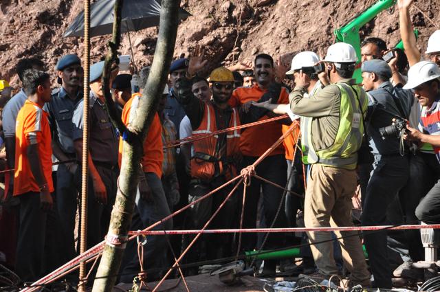 A rescued workers waves at the mediapersons as he comes out of the tunnel where he had been trapped for more than a week. (HT Photo)