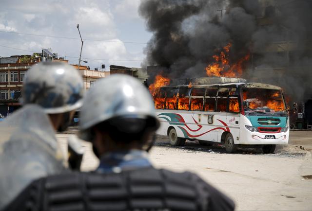 Police stand in front of a burning passenger bus after it was set on fire by unidentified protesters during the nationwide strike, called by the opposition parties against the constitution, in Kathmandu, Nepal. (Reuters Photo) Police stand in front of a burning passenger bus after it was set on fire by unidentified protesters during the nationwide strike, called by the opposition parties against the constitution, in Kathmandu, Nepal. (Reuters Photo)