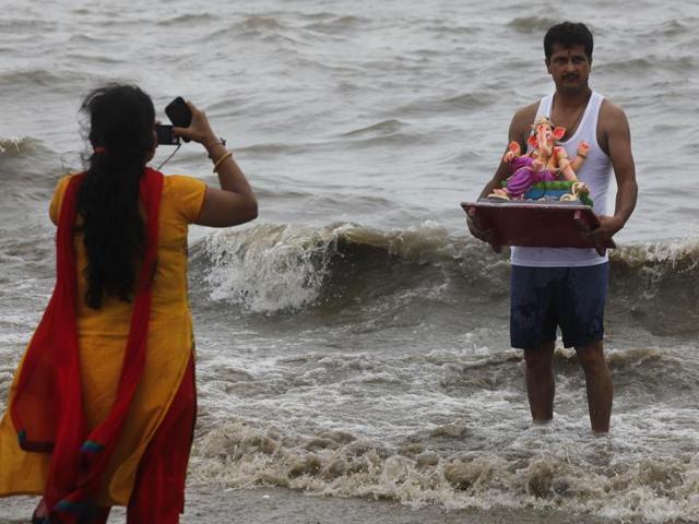 A devotee poses with the Ganesh idol before the immersion at Girgaon Chowpatty in Mumbai. (Arijit Sen/HT photo)