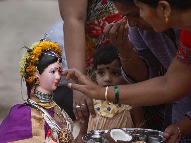 A child looks on intently as other devotees offer prayers before immersing the idols of Gauri and Ganpati during the fifth day of immersions at Girgaom Chowpatty in Mumbai. (Arijit Sen/HT photo)