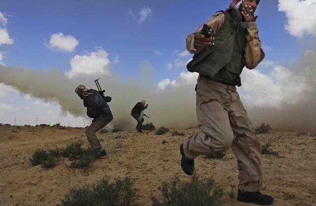 Libyan rebels run for cover as they shell pro Gadhafi forces along the front line near Brega, Libya, Saturday, April 2, 2011 (AP Photo/Altaf Qadri) (AP)