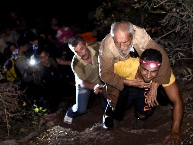 A man helps an elderly man to climb a slope after they arrived, with other refugees and migrants, to the Greek island of Lesbos after crossing the Aegean sea from Turkey. (AFP) A man helps an elderly man to climb a slope after they arrived, with other refugees and migrants, to the Greek island of Lesbos after crossing the Aegean sea from Turkey. (AFP)