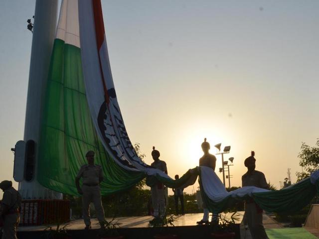 Cops on duty hold the 40 feet long tricolour, which would fly at a height of 170 feet in Amritsar during its hoisting ceremony in Amritsar on Sunday. (Sameer Sehgal/HT Photo)