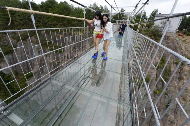 Tourists look down as they walk on a glass suspension bridge at the Shiniuzhai National Geo-park in Pinging county, Hunan province, China. (REUTERS)