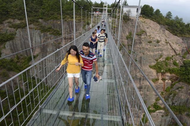 Tourists walk on a glass suspension bridge at the Shiniuzhai National Geo-park. (REUTERS)