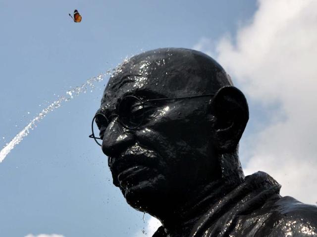 A butterfly flutters as an Indian labourer showers water onto a statue of Mahatma Gandhi on the eve of Gandhi Jayanti at Gandhi Park in the eastern city Bhuabenswar . Gandhi Jayanti is also observed as International Day of Non-Violence and is celebrated to mark the birth anniversary of Mahatma Gandhi on October 2 annually. (AFP Photo) 