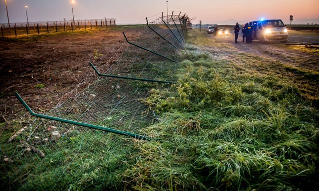 Police officers stand in front of a damaged fence after migrants entered the Eurotunnel site in Coquelles, northern France. (AFP) Police officers stand in front of a damaged fence after migrants entered the Eurotunnel site in Coquelles, northern France. (AFP)
