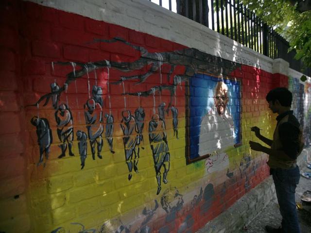 An artist makes Mahatma Gandhi’s graffiti near Delhi University on his 146th birth anniversary in New Delhi. (Ravi Choudhary/HT photo)