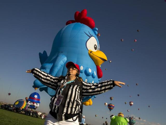 A launch director signals attendees to get out of the way as a hot air balloon lands on the first day of the 2015 Albuquerque International Balloon Fiesta. (REUTERS)