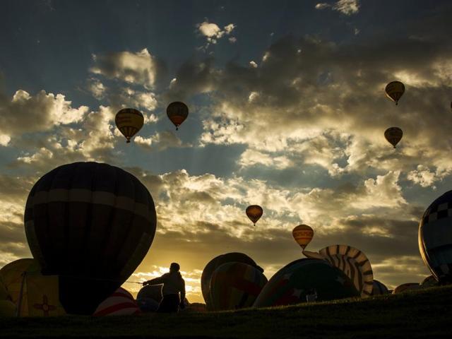 A man holds a guide line as he stands in front of hot air balloons being prepared for lift off on the first day of the 2015 Albuquerque International Balloon Fiesta in Albuquerque, New Mexico, October 3, 2015. (REUTERS)