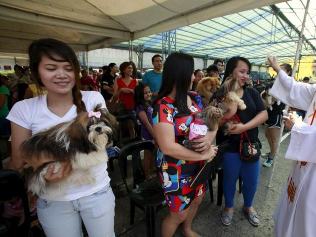 Xander Carandang, a Catholic priest, sprinkles holy water on people and their pets during a pet blessing at the Greenhills shopping mall in Manila. (REUTERS)