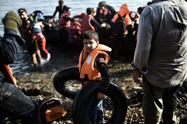 A young boy holding rubber ring buoys is pictured after reaching with other refugees and migrants aboard dinghies the Greek island of Lesbos, crossing the Aegean sea from Turkey. (AFP)