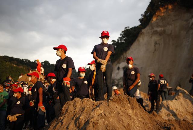 Firefighters wait for instructions to start their turn at searching for survivors at the site of a mudslide as the sun sets in Cambray, a neighbourhood in the suburb of Santa Catarina Pinula, on the outskirts of Guatemala City. (AP Photo)