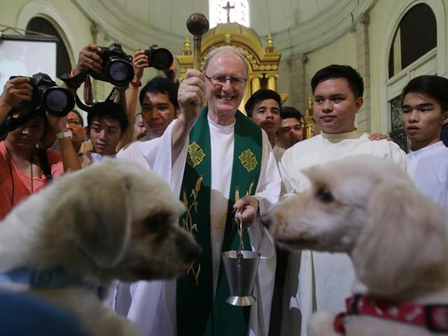 A Catholic priest smiles as he sprinkles holy water on two dogs during animal blessing rites at the Malate church in Manila. (AP)