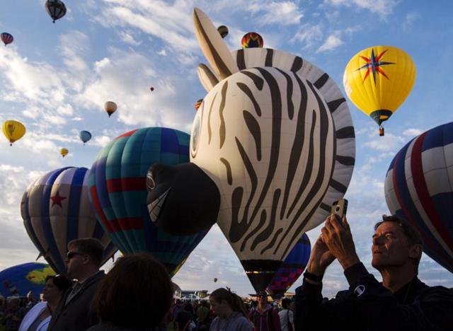 A man uses his phone to take pictures as hundreds of hot air balloons lift off at the Fiesta. Organizers say it’s one of the most photographed events in the world. (REUTERS)