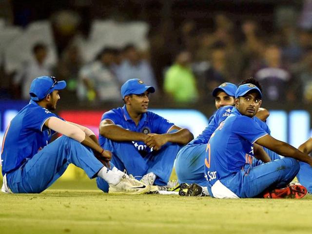 Indian cricketers sit near the pitch after play in the second innings was halted due to crowd disturbance. (PTI Photo)