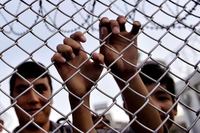 A migrant grabs a razor wire-topped fence as the Greek prime minister Alexis Tsipras visits a refugee and migrant registration camp in Mytilene, on the Greek island of Lesbos, on October 6, 2015. (AFP Photo) A migrant grabs a razor wire-topped fence as the Greek prime minister Alexis Tsipras visits a refugee and migrant registration camp in Mytilene, on the Greek island of Lesbos, on October 6, 2015. (AFP Photo)