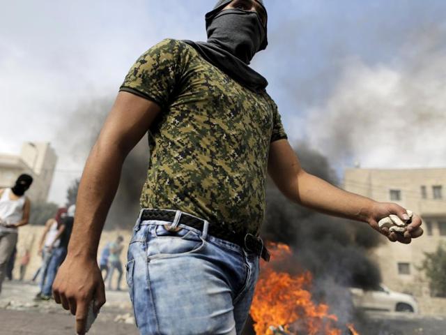 A masked Palestinian holds stones during clashes with Israeli police in Sur Baher, a village in the suburbs of Arab east Jerusalem. (REUTERS Photo)