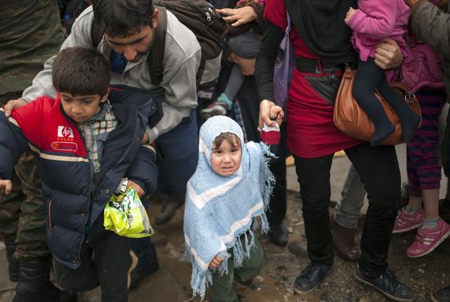 Macedonian police officers control a crowd of migrants and refugees as they prepare to enter a camp after crossing the Greek border into Macedonia near Gevgelija. (AFP)