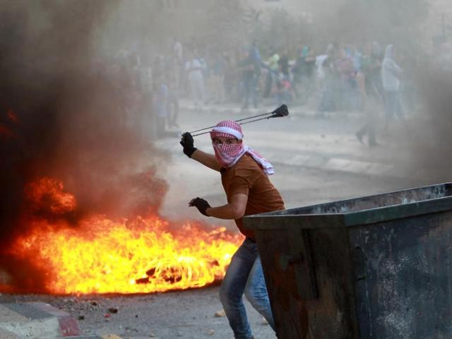 A Palestinian youth uses a slingshot to throw stones towards Israeli security forces (unseen) during clashes at the main entrance of the West Bank town of Bethlehem. (AFP Photo)