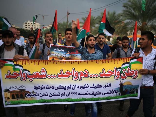 Palestinian students hold national flags and a slogan which reads in Arabic "One home, One blood, One nation" during a demonstration in Gaza City. (AFP Photo)