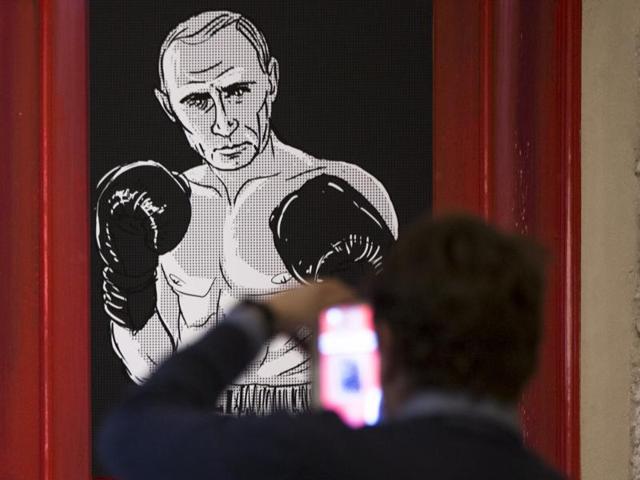 A man takes a picture of an artwork depicting Russian President Vladimir Putin as boxing legend Muhammad Ali during the "Putin Universe" exhibition in Moscow. (AP Photo)