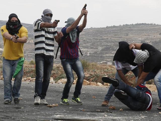 Infiltrated members of the Israeli security forces detain a Palestinian stone thrower and aim their weapons at fellow protesters during clashes in Beit El, on the outskirts of the West Bank city of Ramallah. (AFP Photo)