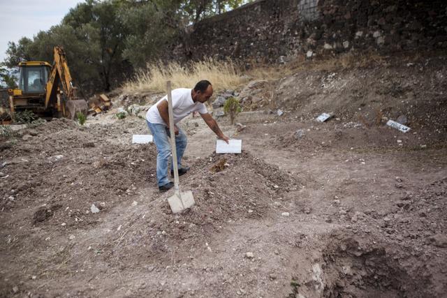Christos Mavrakidis, an employee of the Mytilene Charity Institutions, adjusts a tombstone on the grave of a migrant who drowned at sea. (REUTERS) Christos Mavrakidis, an employee of the Mytilene Charity Institutions, adjusts a tombstone on the grave of a migrant who drowned at sea. (REUTERS)