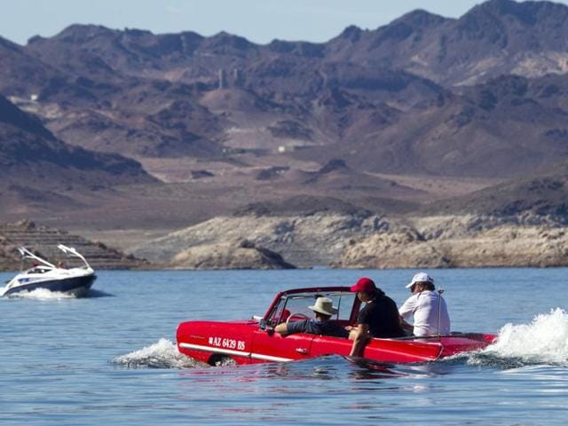 A speedboat passes by a 1963 Amphicar. (REUTERS)