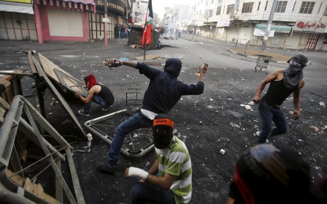 A masked Palestinian protester throws a molotov cocktail at Israeli troops during clashes in the West Bank city of Hebron. Tensions have surged in 11 days of violence in which four Israelis and 17 Palestinians - including several Palestinians shot by police, have been killed in Jerusalem, the Israeli-occupied West Bank, Gaza and in Israeli cities. (REUTERS Photo)