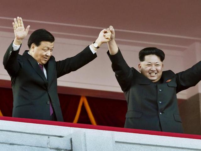 North Korean leader Kim Jong Un (R) takes the hand of senior Chinese Communist Party official Liu Yunshan on a balcony overlooking Kim Il Sung Square. (REUTERS)