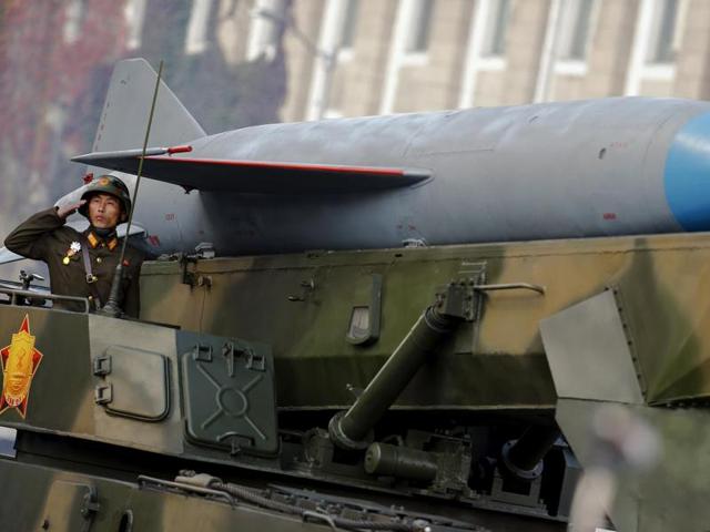 A soldier salutes from atop vehicle carrying a missile past a stand with North Korean leader Kim Jong Un. (REUTERS)