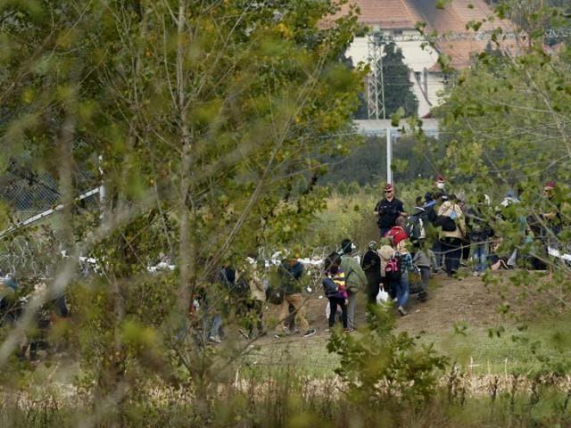 Hungarian police officer looking at migrants as they enter to Hungary. (REUTERS) Hungarian police officer looking at migrants as they enter to Hungary. (REUTERS)