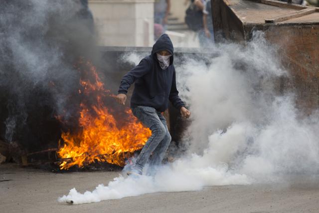Palestinian kicks a tear gas canister during clashes with Israeli troops near Ramallah, West Bank. Palestinians carried out two stabbing attacks in Jerusalem on Saturday before being shot dead by police forces, the latest in a series of stabbing attacks against civilians and soldiers that have spread across Israel and the West Bank in the past week. (AP Photo)