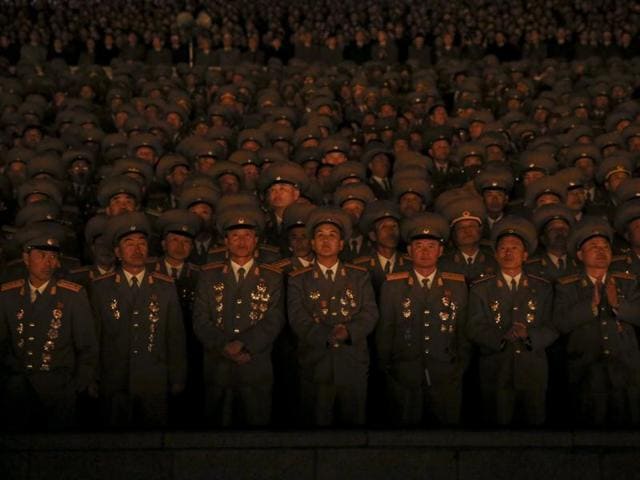 Senior North Korean military officers are lit by light from torches as they follow the performance on Pyongyang's main Kim Il Sung Square. (REUTERS)
