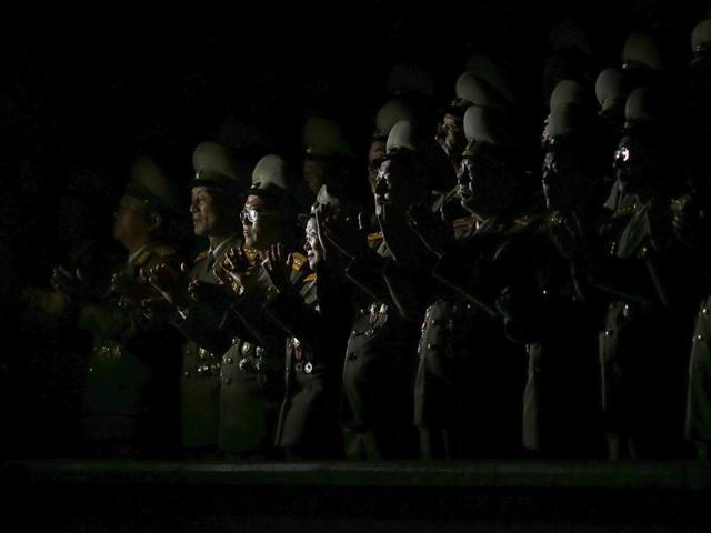 Senior North Korean military officers are lit by light from a camera as they follow the performance on Pyongyang's main Kim Il Sung Square. (REUTERS)